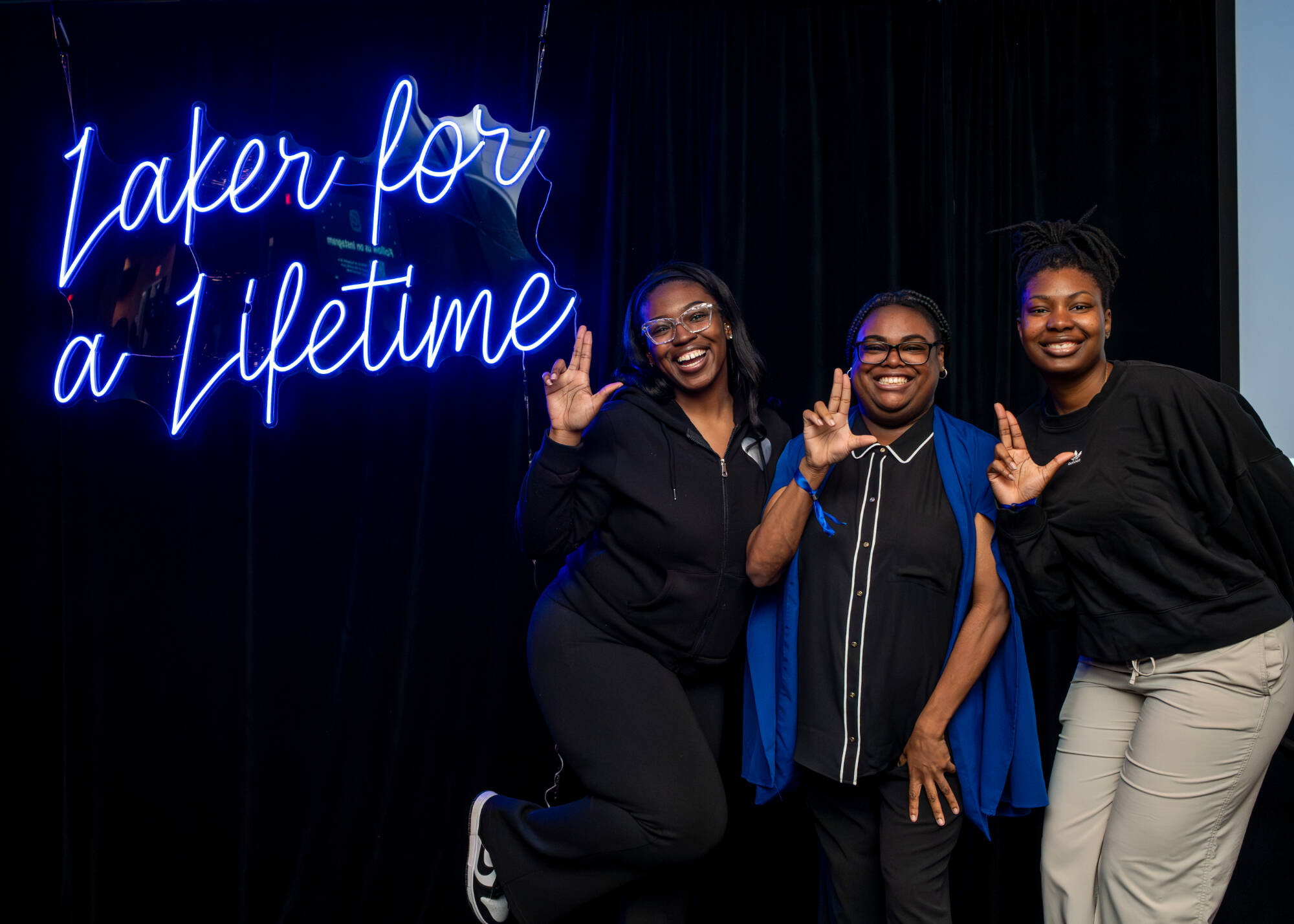 Three women next to Laker for a Lifetime sign